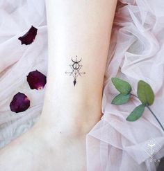 a woman's foot with a small tattoo on the ankle and purple flowers behind her