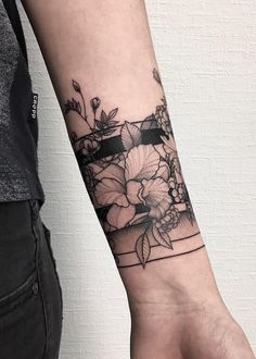 a woman's arm with flowers on it and a black ribbon around the wrist