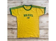 This stylish crop tee features vibrant designs that celebrate Brazil's rich football culture, making it perfect for fans of all ages. With its trendy Y2K style, it's an ideal addition to any football lover's wardrobe and makes a fantastic gift for those who adore Brazilian football.  Features  Vibrant Brazil Design: Showcases eye-catching graphics inspired by Brazil's football heritage, perfect for fans. Trendy Y2K Style: A stylish crop fit that pairs well with shorts, jeans, or skirts for a fun Brazil Design, Football Heritage, Brazil Top, Football Brazil, Brazilian Football, Y2k Baby Tee, Baby Tees, Crop T Shirt, Baby T Shirts