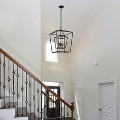 a foyer with white walls and wood floors, chandelier hanging from the ceiling