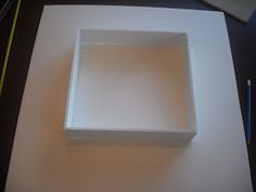 a square white box sitting on top of a table next to a pencil and paper