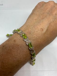 This Peridot bracelet is very lively and bright. The stones are deep colors and well matched. The sterling silver is plated with rhodium to protect the bracelet from tarnish and give the appearance of white gold. 7.5 inches My jeweler can shorten it and he charges a $20 fee All jewelry is shipped in a nice gift box. Check out our over a THOUSAND great reviews Engraving is $4 per letter and is not always perfect depending on the piece. It can take a few days if the jeweler is busy. This is payabl Sterling Silver Bracelet With Green Gemstone, Green Sterling Silver Bracelets Fine Jewelry, Green Sterling Silver Bracelets, Fine Jewelry, Green Sterling Silver Jubilee Bracelet, Certified Green Sterling Silver Bracelets, Silver Tennis Bracelet, Peridot Bracelet, Blue Topaz Bracelet, Topaz Stone