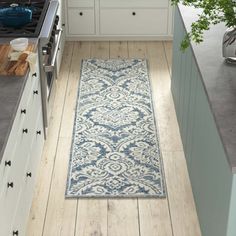 a kitchen with an area rug on the floor next to the stove and cabinets in it