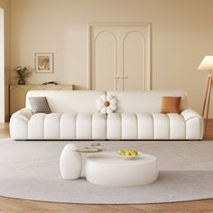 a living room with a white couch and table in the middle, on top of a wooden floor