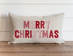 a merry christmas pillow sitting on top of a wooden table