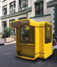 a yellow bus is parked in front of a building with people sitting on the benches