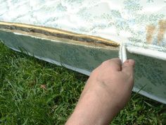 a person is writing on the edge of a mattress that has been placed in the grass