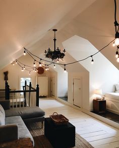 a living room filled with furniture and lots of lights hanging from the ceiling above it