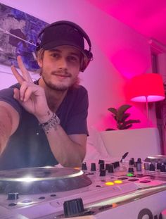 a young man making the peace sign in front of a dj's turntable