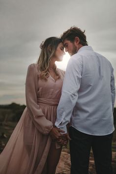 a man and woman standing next to each other in front of the sun holding hands