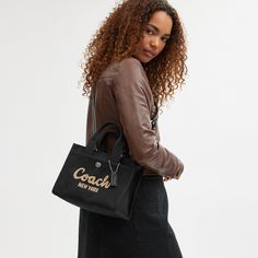 Carry as much (or as little) as you like with our lightweight Cargo tote. Detailed with our cursive Coach script embroidery and iconic turnlock closure this compact 26 has an open interior with room for an iPad two outside pockets for easy organization and a removable webbing strap for shoulder or crossbody wear. Crafted to last this versatile carryall is made with cotton sourced from farms that use regenerative agricultural practices* and inspired by our commitment to reducing our impact on the Luxury Calvin Klein Shoulder Bag For Everyday, Luxury Calvin Klein Shoulder Bag, Luxury Everyday Calvin Klein Shoulder Bag, Coach Hamdbags, Coach Bags Handbags 2022, Everyday Calvin Klein Shoulder Bag, Coach Handbags Coach, Coach Bag Blck, Black Crossbody Bag Coach