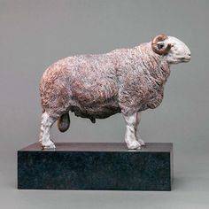 a statue of a sheep standing on top of a black block