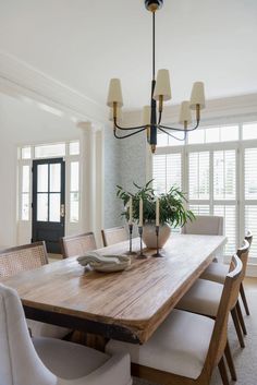 a dining room table with white chairs and a potted plant on the centerpiece