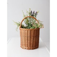 a wicker basket filled with flowers sitting on top of a white counter next to a wall