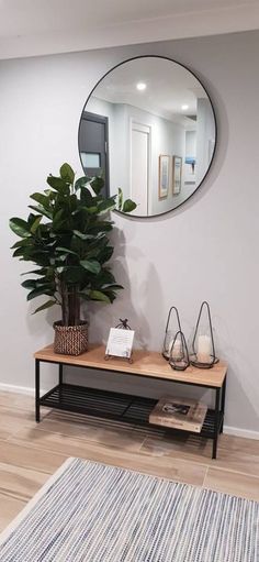 a mirror on the wall above a table with a potted plant next to it