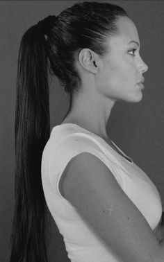 a black and white photo of a woman with her hair in a pony tail ponytail