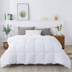 a white comforter on a bed in a room with wood flooring and plants