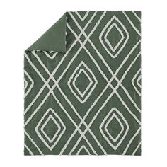 a green and white blanket with diamond shapes on the front, along with a matching pillow