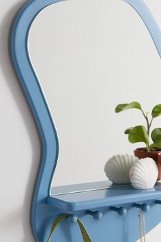 a blue shelf with a potted plant on it and a mirror in the background