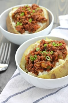 two bowls filled with food sitting on top of a table next to a fork and knife