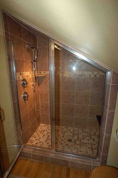 a walk in shower sitting inside of a bathroom next to a toilet and wooden floor