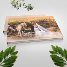 a wedding photo book with two horses in the background and greenery around it on a white surface