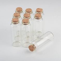 six empty glass bottles with corks on the top and one filled with sand inside