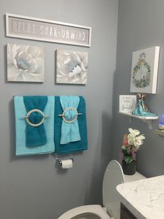 a white toilet sitting in a bathroom next to a wall mounted towel rack with pictures on it