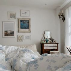 a bedroom with pictures on the wall and a bed in front of a dresser next to a window