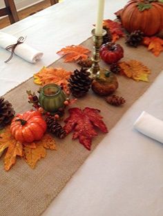 the table is decorated with autumn leaves and pumpkins, candlesticks and pine cones