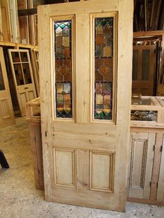 a wooden door with stained glass panels in a room full of shelves and cabinets on the floor