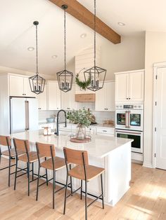 a kitchen with white cabinets and wooden flooring has an island in front of the stove