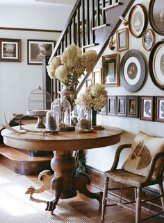 a wooden table sitting under a stair case next to a set of stairs with pictures on the wall