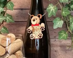 a bottle of wine with a teddy bear on it next to some corks and leaves