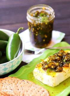 there is a green plate with crackers on it and some pickles in the background