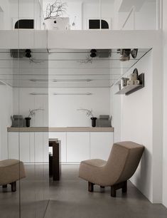 two chairs are in the middle of a room with mirrors on the wall above them