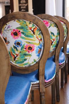 the chairs are lined up in rows with colorful flowers on them and blue cushiones