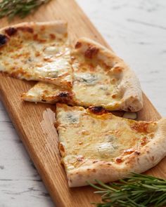 two slices of cheese pizza on a wooden cutting board with fresh rosemary sprigs