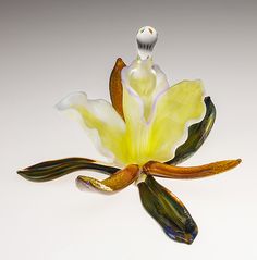 a yellow flower is sitting on a white surface with an object in the foreground