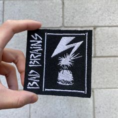 a person holding up a patch with a lightning bolt on it and the words nirvana rock written in white