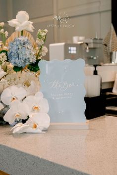 flowers are sitting on the counter next to a sign