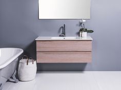 a white bath tub sitting next to a bathroom sink under a large mirror on the wall