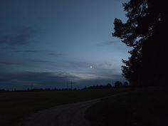 the sun is setting over a field with trees