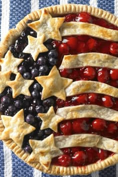 an american flag pie with blueberries and cherries in the shape of stars on top