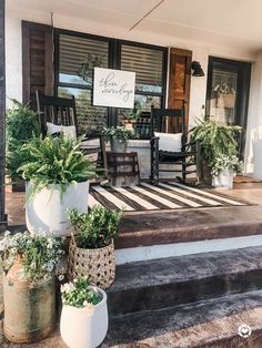 some potted plants are sitting on the front porch steps with chairs and table in the background