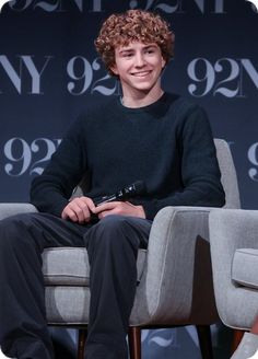 a smiling young man sitting in a chair