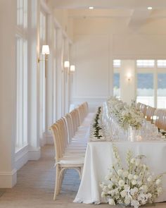 a long table with white flowers and wine glasses on it is set up for a formal function