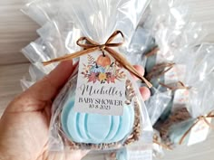 a hand holding a blue baby shower soap in it's package with the label on it