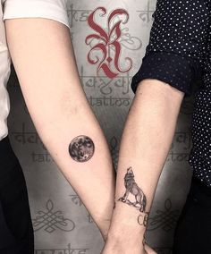 two people are holding hands with tattoos on their arms and one has a dog in the middle