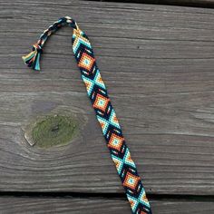 a multicolored beaded bracelet on a wooden surface with a hook in the middle